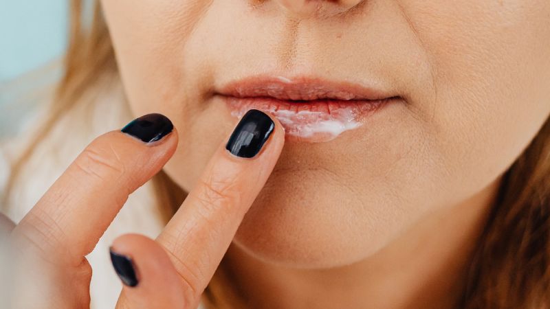 žena si natírá krém na permanentní makeup rtů